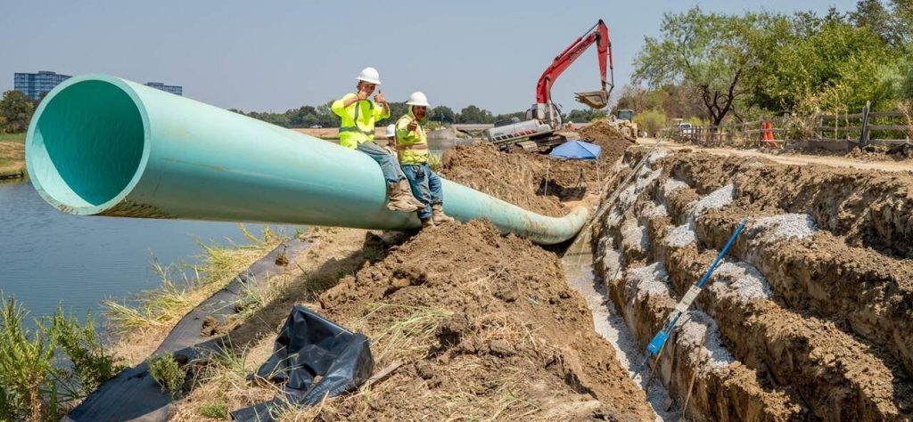 two men sitting on a pipeline in the Cottonwood Valley nieghborhood pipeline rehab