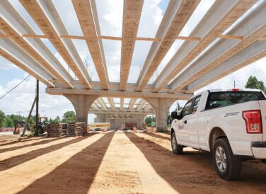 truck parked beneath bridge beams for SH 249 Tomball Tollway