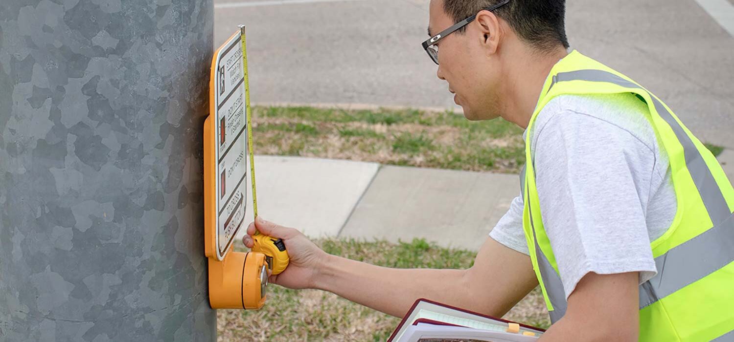 man inspecting street crossing signal button