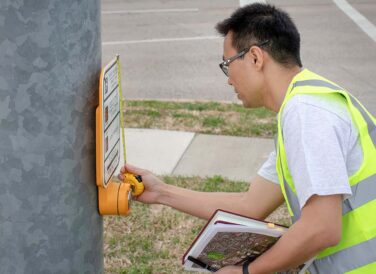 man inspecting street crossing signal button