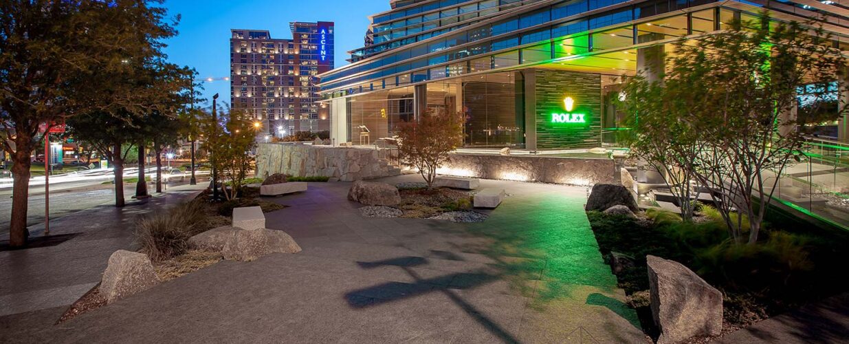 Rolex Building plaza at night with Dallas cityscape