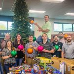 Frisco office volunteers holding ornaments and setting up holiday store for Frisco Family Services.