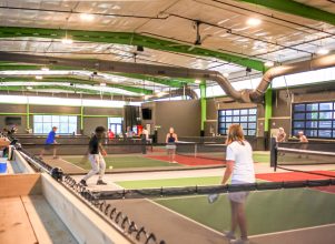 People of all ages playing indoor pickleball at Chicken N Pickle in Grand Prairie, Texas
