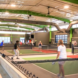 People of all ages playing indoor pickleball at Chicken N Pickle in Grand Prairie, Texas
