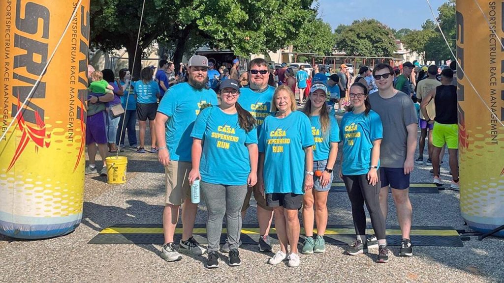 Shreveport employees in front of inflatable arch at the CASA Superhero Run