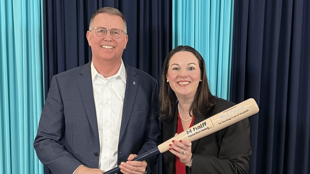 Retired President/CEO Mark Edwards holding his Halff Home Run bat award next to upcoming President and CEO Jessica Baker Daily