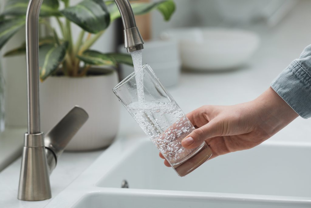 person holding a glass filling it with tap water