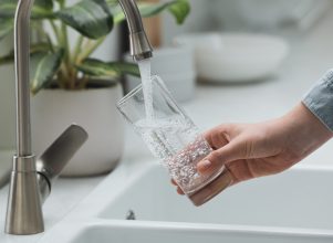 person holding a glass filling it with tap water