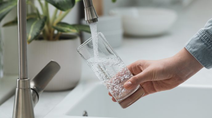 person holding a glass filling it with tap water